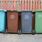 Cztery pojemniki na odpady z numerem 23 w kolorach: niebieskim, brązowym, szarym i zielonym.
