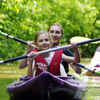 Kobieta i dziewczynka płyną w fioletowym kajaku.