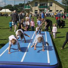 Dzieci gimnastykują się na niebieskiej macie i na boisku.