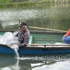 Wędkarze na łódce wypuszczają ryby do jeziora.
