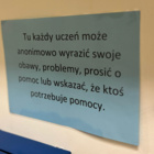 Na morelowej ścianie umieszona jasnoniebieska kartka z napisem 